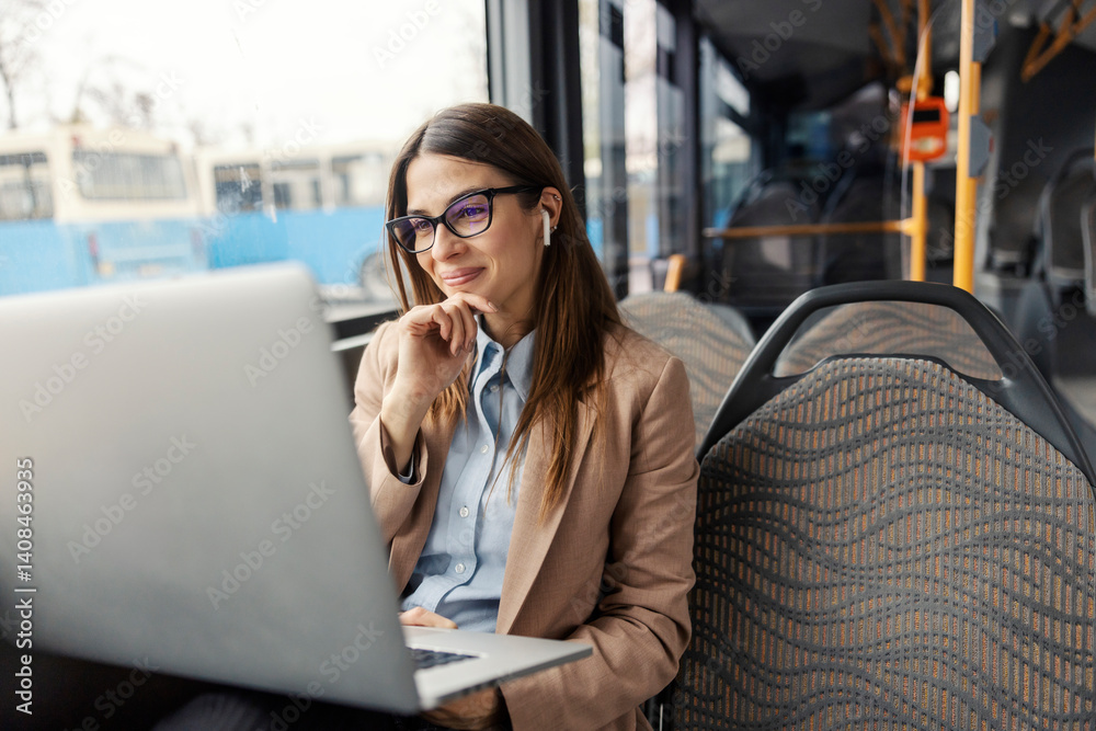 Young chic happy lady sitting in public bus and smiling at laptop during ride.