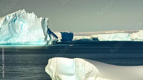 A frozen Arctic landscape with massive icebergs and a deep blue ocean stretching into the distance