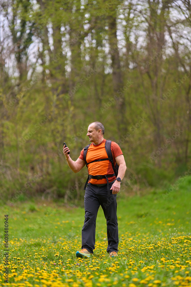 Man hiking with phone in meadow