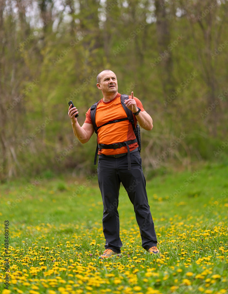 Man pointing while holding phone outdoors