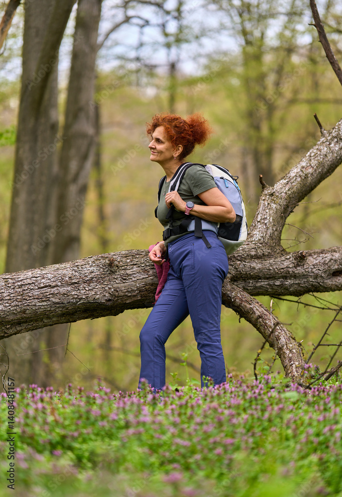 Woman resting on fallen tree in forest