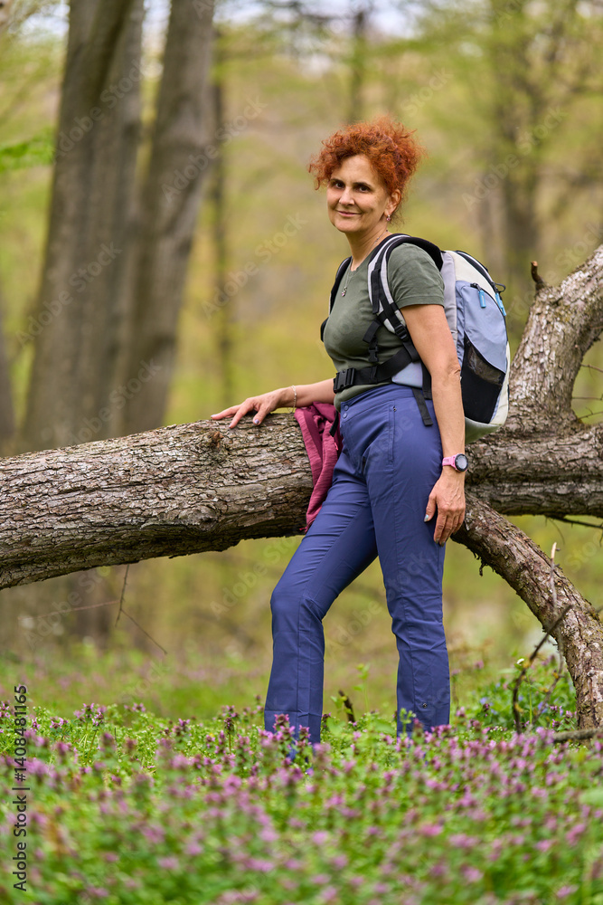 Woman resting on fallen tree in forest
