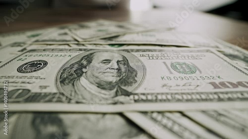 Male hands sliding stack of 100 dollar bills across wooden table and pulling it back. Close-up shot of US currency gesture. Concept of financial decision, money offer, bribe, negotiation.