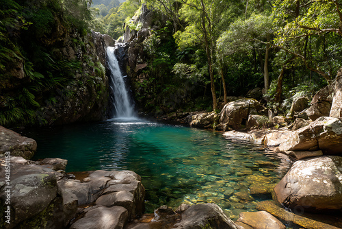 Majestic waterfall cascading over rocks into a clear blue pool, surrounded by dense green foliage and mist rising