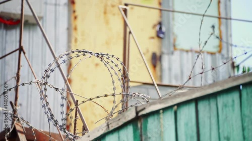 Metal fence with barbed wire, commonly used in prisons or conflict zones. Represents separation, defense, and confinement.