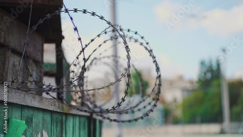 Barbed wire fence with sharp razor coils on top, symbolizing security, protection, and restricted access. Ideal for concepts like prison, border control, or military zone.