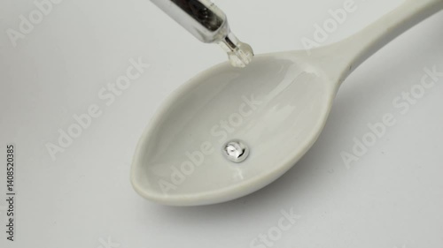 drops of metallic mercury falling onto a white spoon