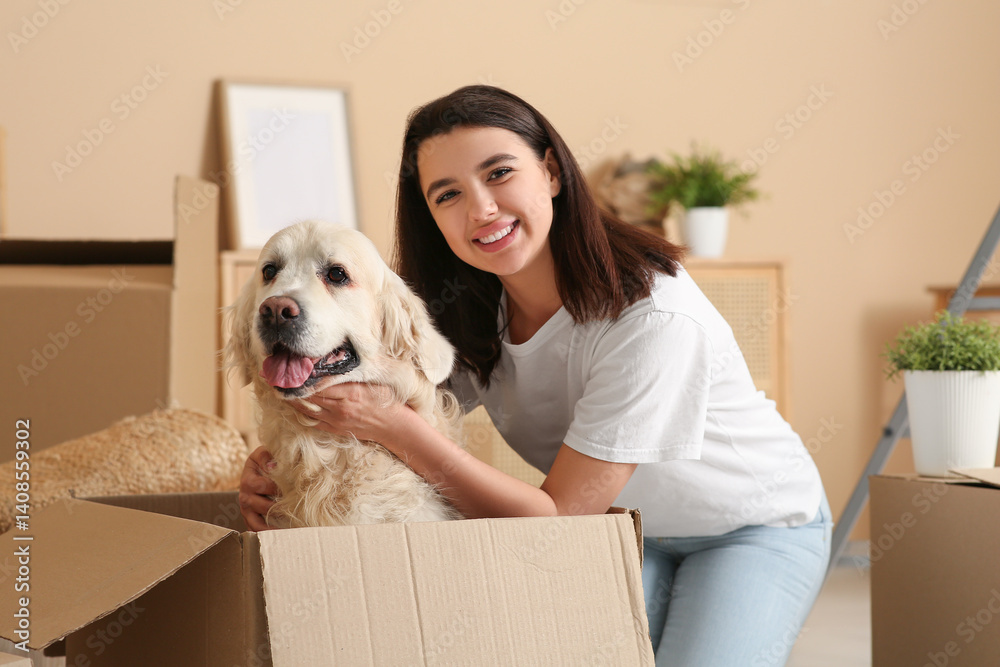 Fototapeta premium Young happy woman and cute Labrador dog with boxes on moving day at home