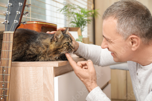 Obraz na płótnie Mature man petting cute cat at home w salonie