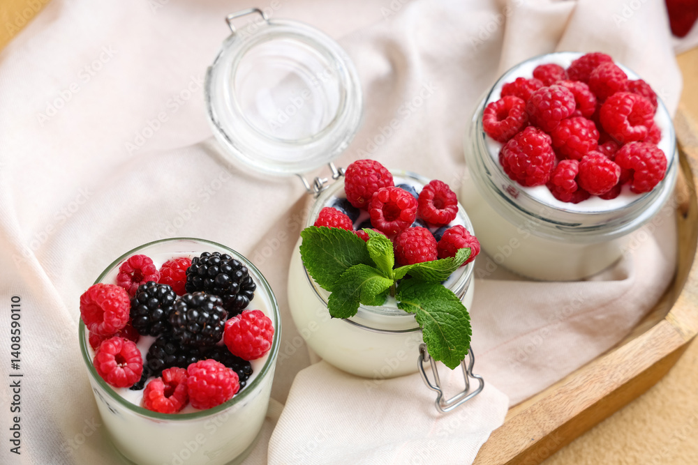 Glass and jars of tasty yogurt with different fresh berries on table, closeup Glass and jars of tasty yogurt with different fresh berries on table, closeup