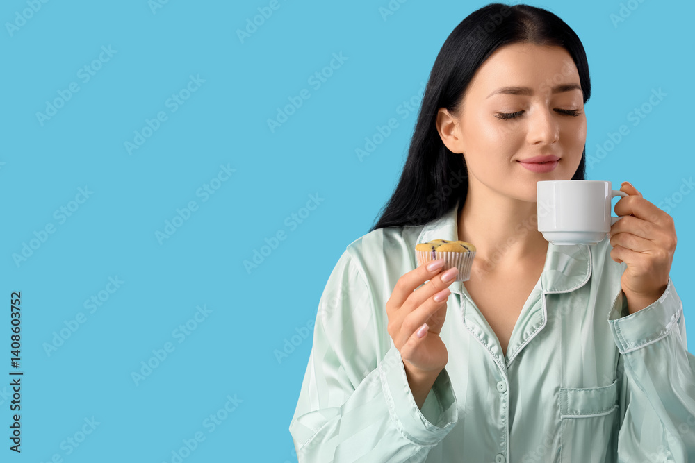 Young woman in pajamas with tasty muffin and cup of coffee on blue background, closeup Young woman in pajamas with tasty muffin and cup of coffee on blue background, closeup