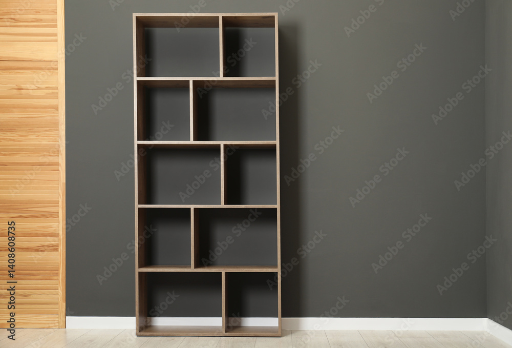 Empty shelving unit and folding screen near grey wall indoors, space for text