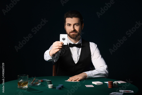 Handsome male banker with poker chips and playing cards at table in casino