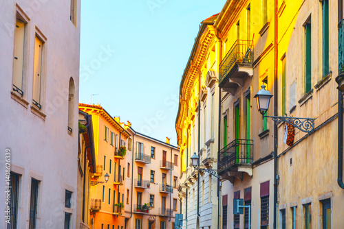 Obraz na płótnie Warm sunlight bathes a charming Italian street lined with colorful historic buildings and balconies. A peaceful, vibrant atmosphere perfect for travel, architecture, or lifestyle themes w salonie
