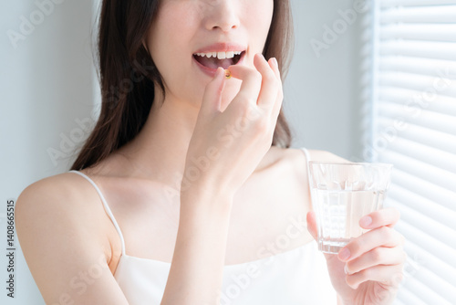 部屋でサプリメントを飲む若い女性