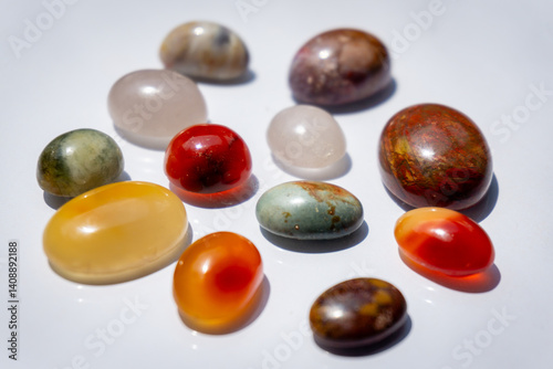 A collection of polished gemstones displays a variety of colors, textures, and unique patterns under soft light.