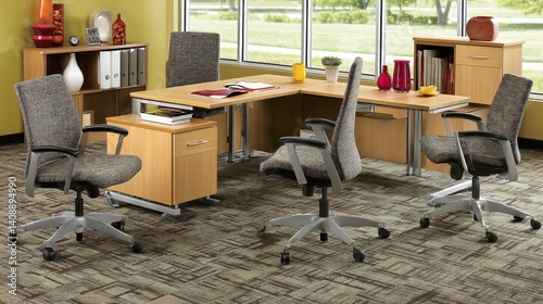 Office interior view chairs circle a wooden desk, natural light floods space