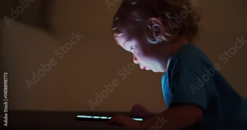 Little child learns to use new  internet technologies. Baby plays with cellphone at home in the evening. Small baby presses by finger on touch screen of the phone.  Child is scrolling on mobile phone.