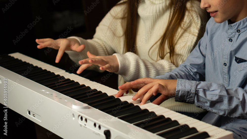 Obraz premium Hands of two children playing the keyboard simultaneously. Practicing piano at home. Education, teaching, learning and friendship concept