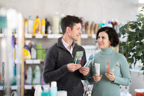 Husband and wife choose toothbrushes of different hardness and different bristles in the supermarket. Married couple buying toothbrush sets for family