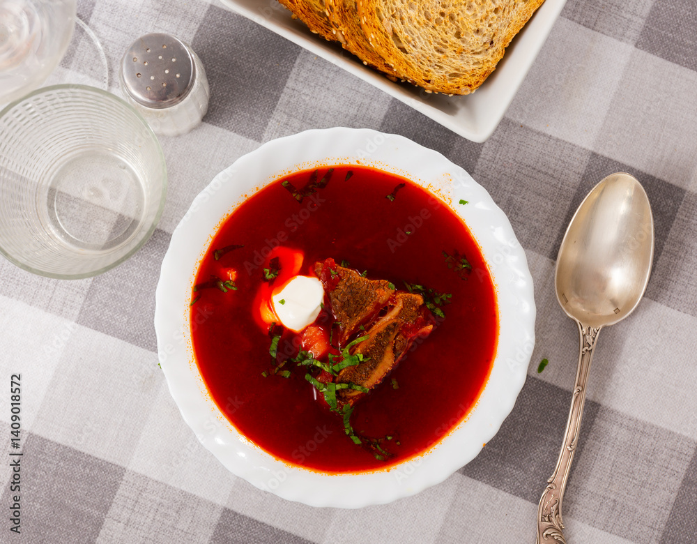 Delicious hearty beet soup with veal meat seasoned with thick sour cream and fresh parsley..