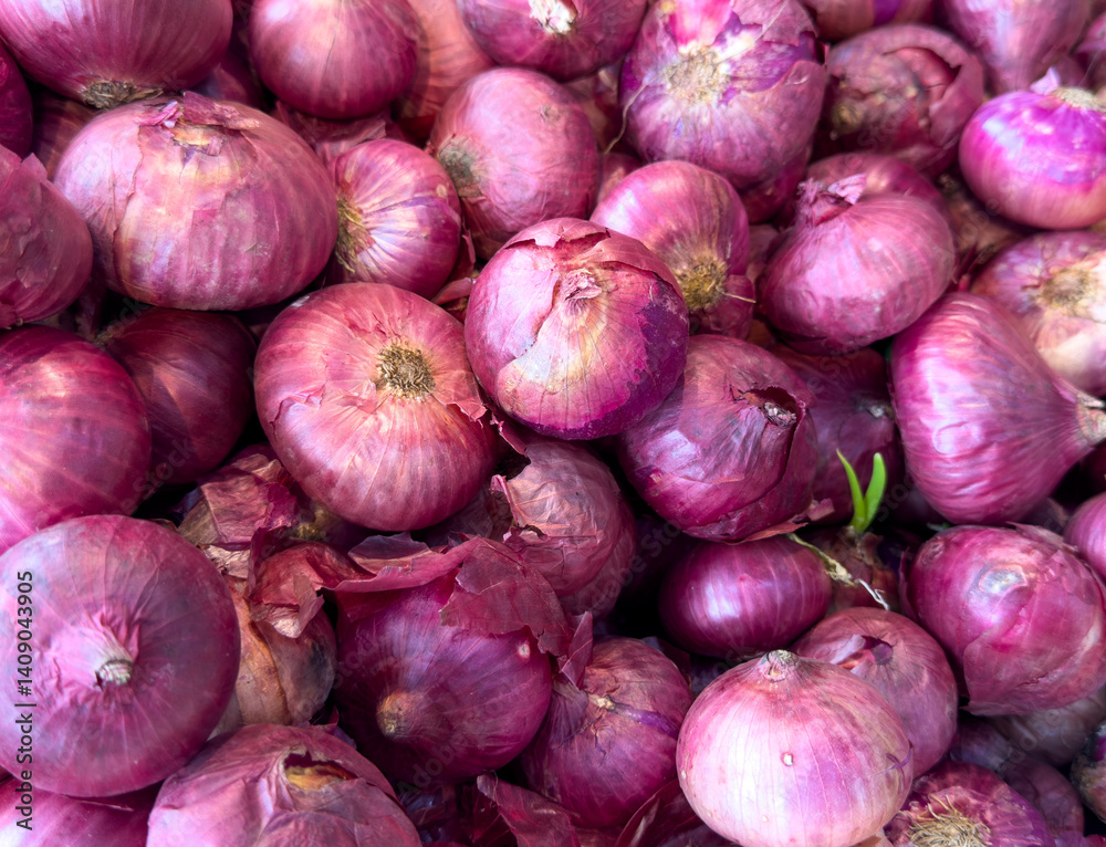 A pile of red onions with some of them being cut off A pile of red onions with some of them being cut off