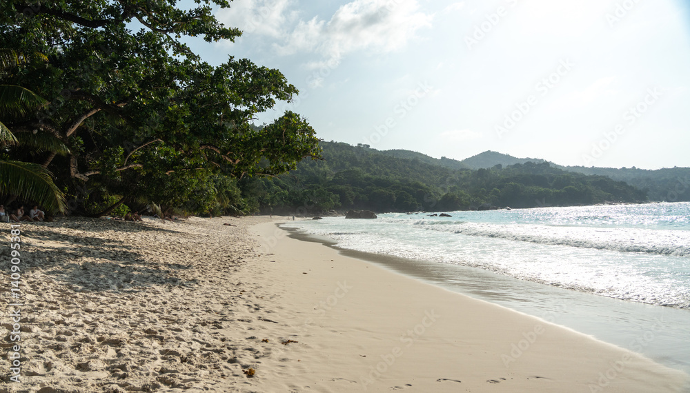 Tropical beach Anse Lazio in Seychelles with soft sand, clear waves, green hills and palm trees