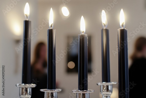 Elegant black candles illuminate minimalist setting, casting enc