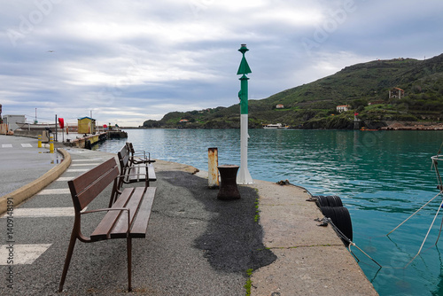 Obraz na płótnie Benches line the edge of a tranquil harbor, where still waters reflect gray skies. w salonie