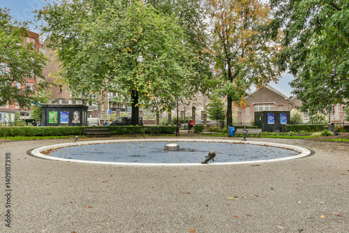 A tranquil park scene featuring a circular fountain at the center, surrounded by lush greenery and pathways, perfect for relaxation and leisure activities.