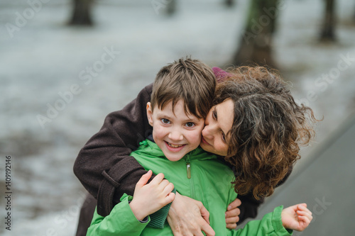 Mother hugging her son outdoors in winter photo