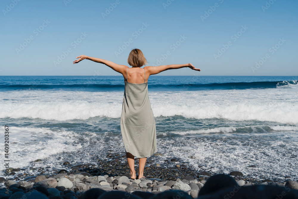 Woman enjoying fresh air on ocean shore with arms outstretched Woman enjoying fresh air on ocean shore with arms outstretched