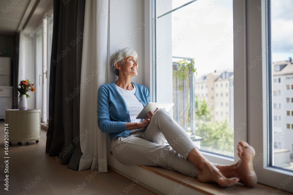 Woman relaxing at home with a tablet by the window during the day Woman relaxing at home with a tablet by the window during the day