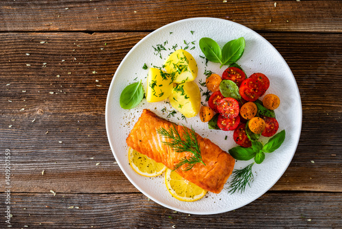 Obraz na płótnie Seared salmon steak with cherry tomatoes and boiled potatoes on wooden table w salonie
