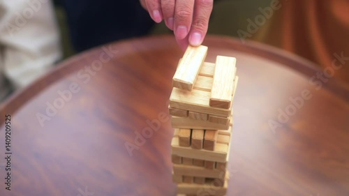 Close up asian diverse group friends playing together with wooden building blocks at home office sitting at the table enjoying time together. Office leisure and board games concept.