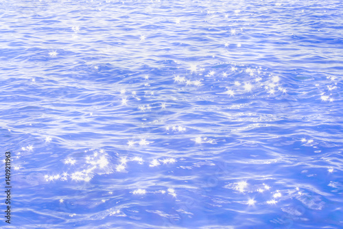 Blue sea surface summer abstract background. Sun light star glare on blue blurred sea water natural background.