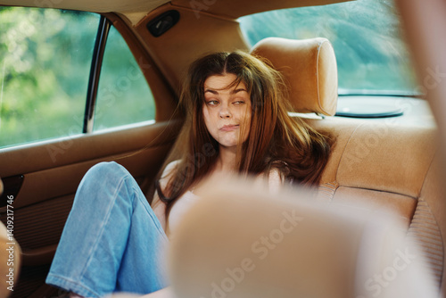 A young woman with messy hair sitting in a car, expressing boredom or frustration in a casual outfit, capturing a relatable moment of travel discomfort.
