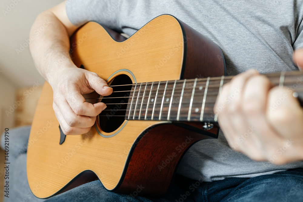 Fototapeta premium Close-up of a man's hands playing the guitar and strumming chords
