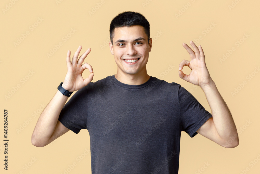 Cheerful contented attractive man enjoys success at work. Handsome young guy with smart watch in casual looks at camera and shows okay gesture isolated on light background, panorama, empty space Cheerful contented attractive man enjoys success at work. Handsome young guy with smart watch in casual looks at camera and shows okay gesture isolated on light background, panorama, empty space