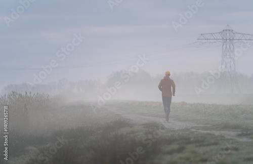 Obraz na płótnie Man running in the foggy, Dutch countryside on a cold morning. w salonie