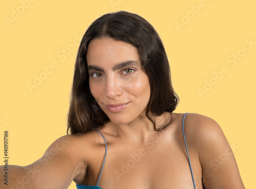 Attractive young woman taking a selfie with yellow background