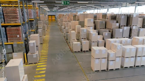 A vast warehouse reveals rows of stacked cargo boxes and shelves, highlighting efficient storage and organization. The aerial view showcases the vastness and orderliness of the space.