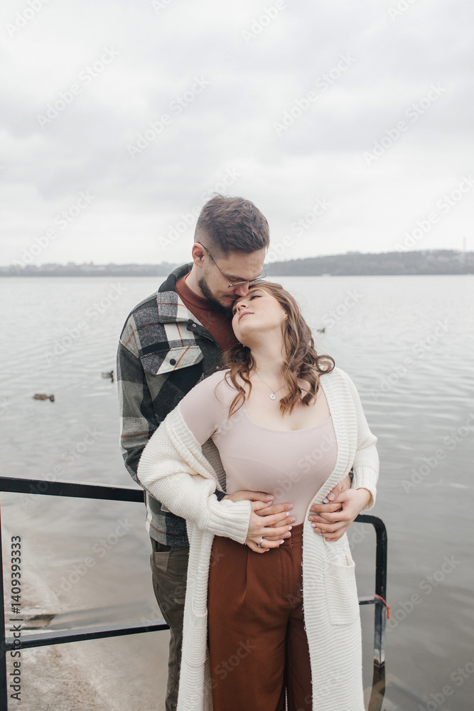 Fototapeta premium Young couple in stylish clothes on a walk. Romantic date outdoors. Walk, kisses and hugs