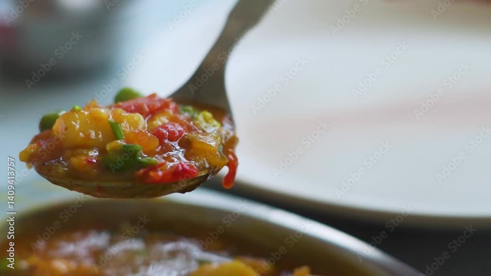 Closeup shot of Indian food being served on a plate with a spoon. Aloo mutter curry being served on a plate during the lunch. Indian food background with copy space. Food is being placed on a plate.