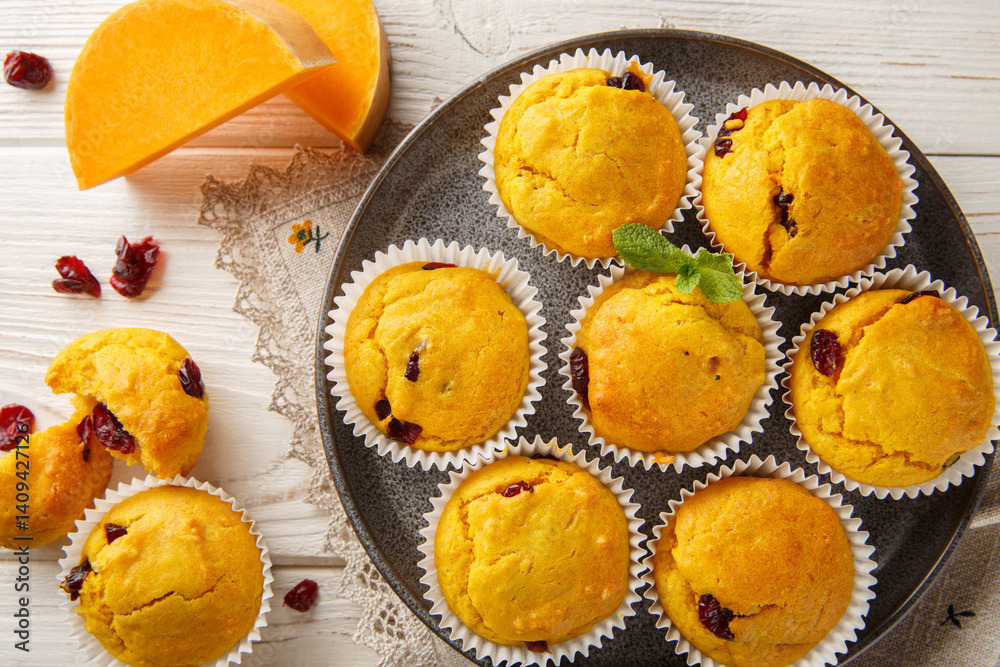 Homemade muffins with pumpkin puree, dried cranberries and spices close-up in a plate on the table. Horizontal top view from above