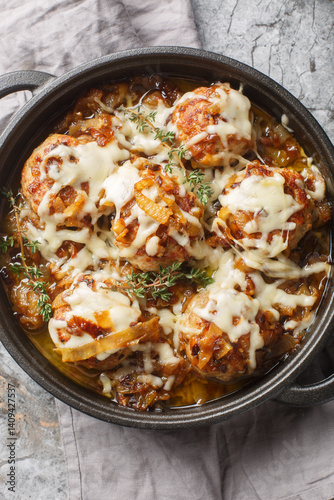 Obraz na płótnie French onion meatballs smothered in rich caramelized onion gravy and topped with melty Gruyere cheese closeup on the pan on the table. Vertical top view from above w salonie