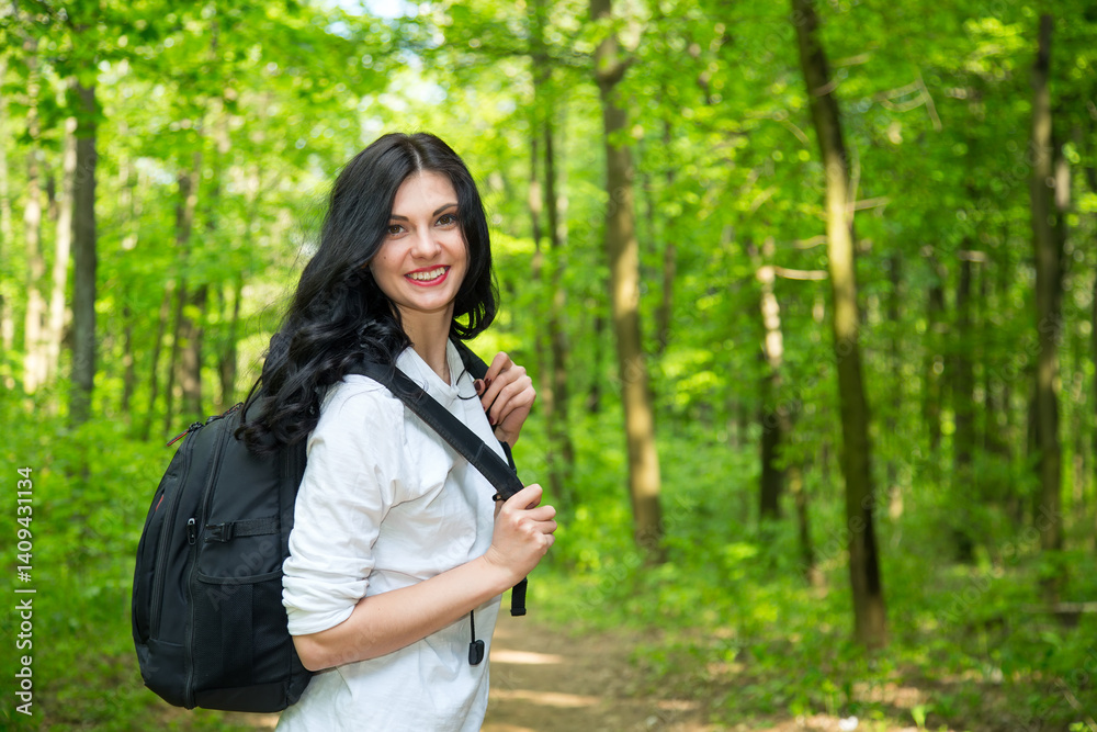 Young woman tourist. Female is walking with a backpack on a green forest. Young woman tourist. Female is walking with a backpack on a green forest.