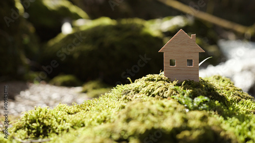 Eco home house wooden icon model in the sunny nature with river.
