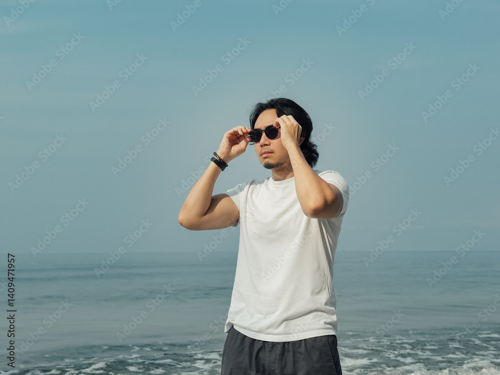 Obraz premium Man wears white t-shirt and sunglasses enjoy walking on the beach.