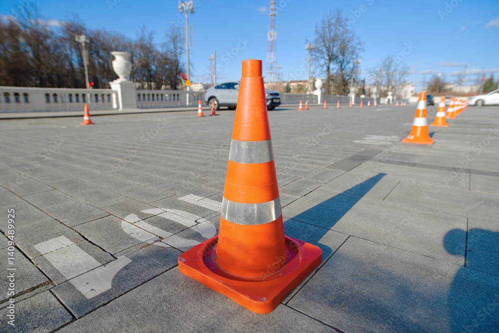 Row of bright orange traffic cones neatly aligned to reserve parking spots in public area. Traffic cones standing in an orderly line to mark and protect reserved parking spaces.